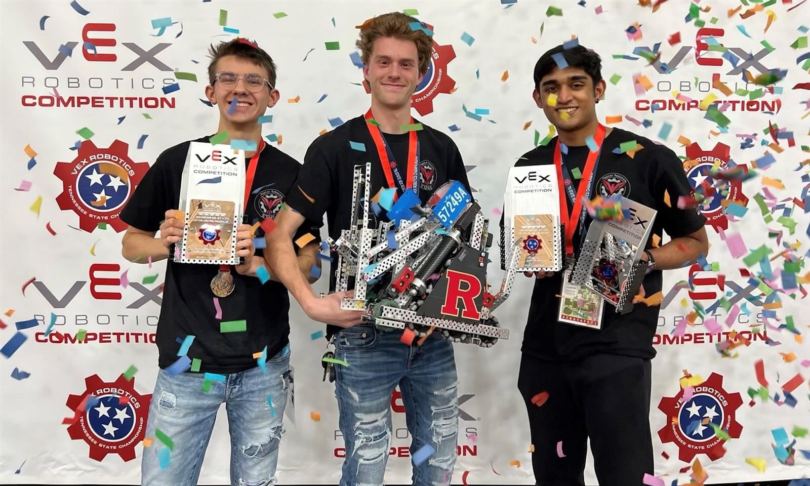 Three boys hold awards